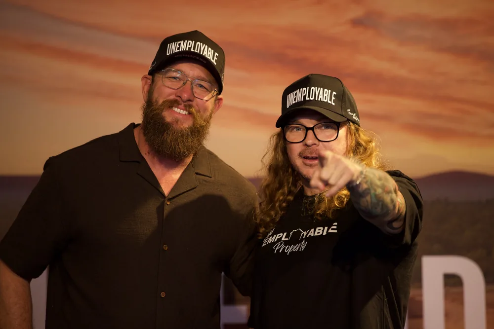 Two attendees in FIND. FUND. DEVELOP caps on the FFD LIVE stage